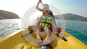 Slowmotion shot of a young family kayaking in a tropical sea and having fun looking at coral reef and tropical fishes