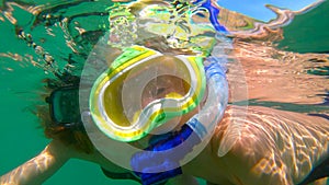 Slowmotion shot of a young woman and her little son snorkeling in a sea