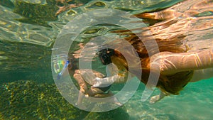 Slowmotion shot of a young woman and her little son snorkeling in a sea