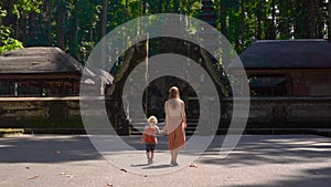Slowmotion shot of a young woman and her son walking inside the Sangeh monkey forest, on the Bali Island, Indonesia.