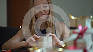 Slowmotion shot of a young woman is packing presents. Present wrapped in craft paper with a red and gold ribbon for