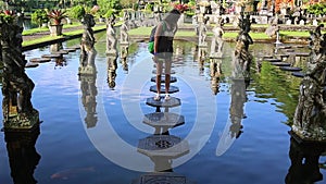 Slowmotion shot of a young woman tourist visiting the Tirta Gangga water palace, former royal palace on the Bali Island