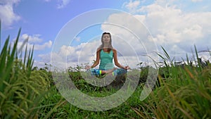 Slowmotion steadicam shot of a young woman doing meditation for Muladhara chakra in a Balinese way