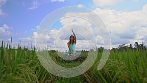 Slowmotion steadicam shot of a young woman doing meditation for Muladhara chakra in a Balinese way