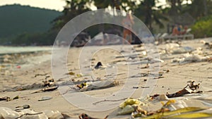 Slowmotion steadycam shot of a beach with fine white sand covered with garbage