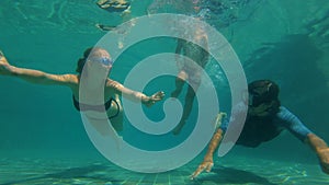 Slowmotion underwater shot of a happy family diving in a swimming pool. Healthy lifestyle, active parents