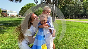 Slowmotion video. Family of a mother and her two kids girl and a boy are running on a green loan holding the Ukranian