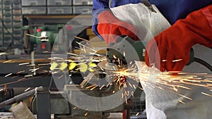 Slowmotion worker in special clothes and gloves grinding metal with circular saw