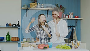 Slowmotion of Young joyful couple have fun dancing and singing while set the table for breakfast in the kitchen at home