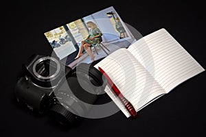 SLR camera, lens, notebook with pen