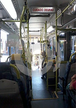 Interior view of a city bus with yellow handrails and black-and-gray seating