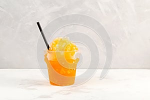 Slushie drink in disposable plastic cup. Orange Granizado. Refreshing summer iced drink. Sweet Shaved ice with natural orange