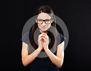 Sly concentrated happy business woman in glasses looking in camera and plotting new earring solution and  fingering on black