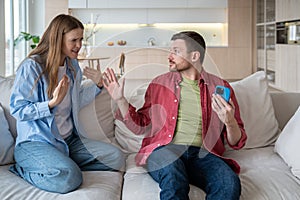 Sly husband cheater hiding smartphone display from unhappy nervous reproachful wife during quarrel