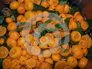 Smal bitter oranges Chinotto and mint leafs boiling in water in a steelpan photo