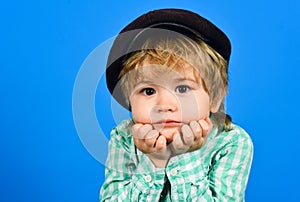 Smal boy in shirt. Boy holds face on hands. Closeup portrait. Fashionable little child in cap. Retro style. Handsome small boy in