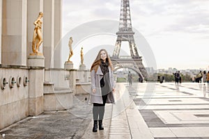 Smaling woman standing on Trocadero square near gilded statues and Eiffel Tower.