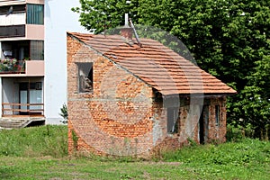 Small abandoned red brick family house with broken missing doors and windows and disconnected electrical wires
