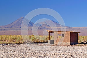 Small adobe house in the desert on salt terrain and near two vol