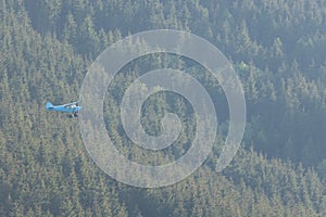 Small airplane flying over a forest