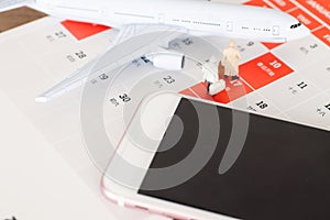 Small airplane model and mobile phone on desk calendar background