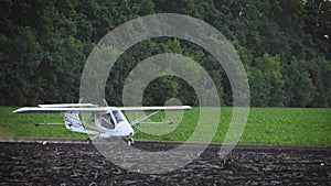 A small airplane takes off from a field.at sunrise