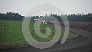 A small airplane takes off from a field.at sunrise