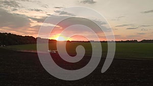 A small airplane takes off from a field.at sunrise