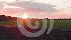 A small airplane takes off from a field at sunrise.