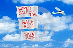 Small airplane towing banner with SALE caption in the sky. Airplane with banners.