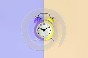 A small alarm clock is located between the violet and cream background areas