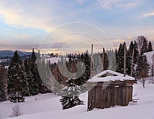 Small alpine village and winter snowy mountains in last sunset sunlight around, Voronenko, Carpathian, Ukraine