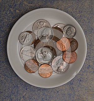 Small american coins on a white saucer