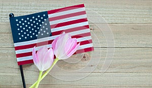 Small American flag with pink tulips on a wood background