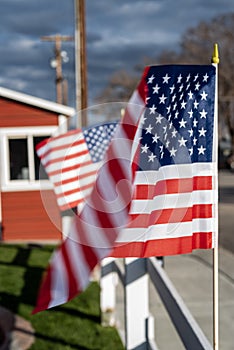 Small American flags on fence along street of small town blowing in wind