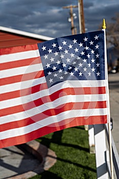 Small American flags on fence along street of small town blowing in wind