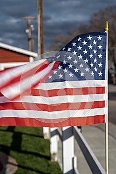 Small American flags on fence along street of small town blowing in wind