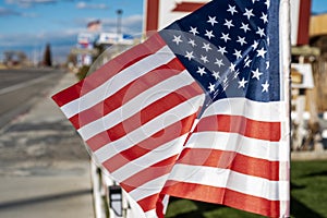 Small American flags on fence along street of small town blowing in wind