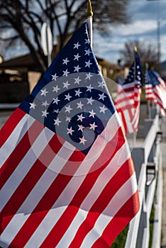 Small American flags on fence along street of small town blowing in wind