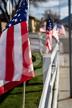 Small American flags on fence along street of small town blowing in wind