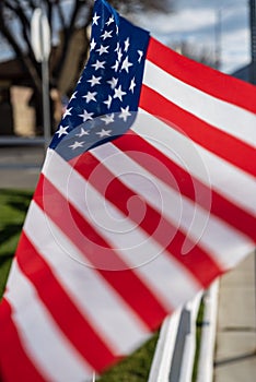 Small American flags on fence along street of small town blowing in wind