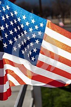 Small American flags on fence along street of small town blowing in wind