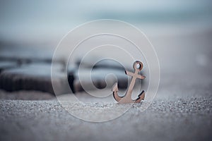 Small anchor emblem restinf upon the sandy shores of the Baltic Sea coast in Germany