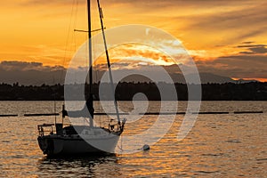 a small anchored sail boat floating at golden hour