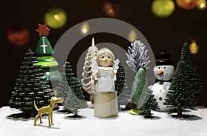 Small Angel read a book on circle wooden chair with dog watching and snow man isolated from Christmas light background