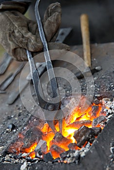 A small anvil, forge and blacksmith tools.