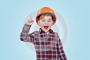 Small architect boy with helmet pointing up to copy space