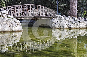 The small artificial lake with the wooden bridge which is reflected on the lake at the National Garden in Athens Greece