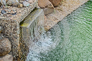 Small artificial waterfall in man made tropical garden. A small decorative waterfall in the garden. Landscape design