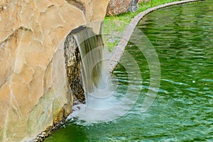 Small artificial waterfall in man made tropical garden. A small decorative waterfall in the garden. Landscape design